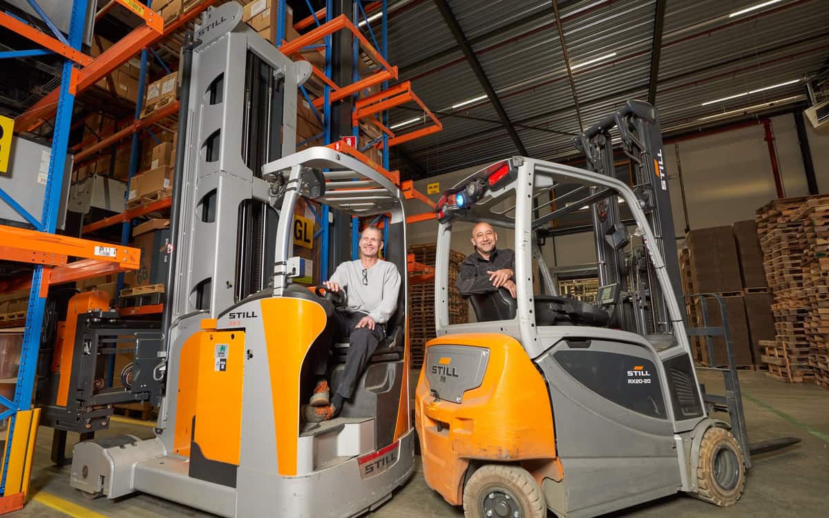 Bij Summit in Almere zitten twee heftruckchauffeurs in het magazijn, elk op een heftruck naast de stellingen